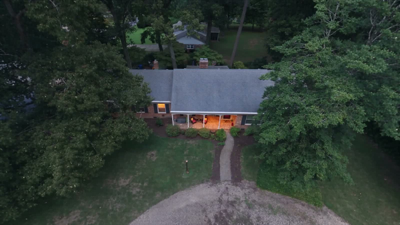 Aerial approach to the brick house and tree-lined grounds
